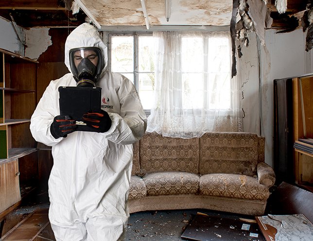 Bioresponse technician wearing an all white hazmat suit at a fire damage scene
